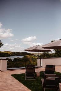 Un patio con sillas y sombrillas con vista a un lago. en Apartamenty Złote Tarasy, en Brodnica Dolna