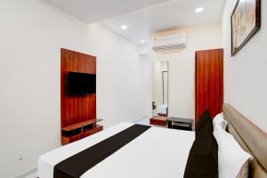 a bedroom with a bed and a tv on the wall at Hotel O Railway in Vadodara +21 photos