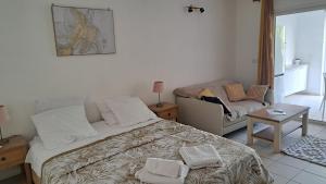 a bedroom with a bed and a table and a couch at Rêve Créole, accès piscine, plage et golf in Saint-François