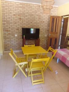 a yellow table and chairs in a living room at Recanto Zen centro Cumuruxatiba in Cumuruxatiba