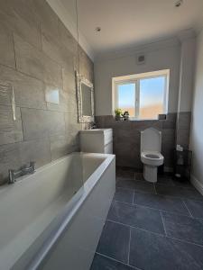 a large bathroom with a tub and a toilet at Tŷ Twt in Pontardawe +17 photos