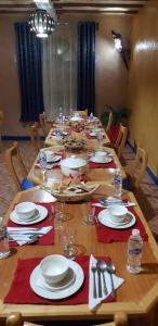 a long wooden table with plates and dishes on it at SUD-EST palace in Ait Gmat