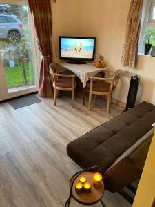 a living room with a television and a table with a couch at Unique folly surrounded by stunning countryside in Kircubbin