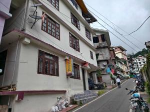 een wit gebouw met rode ramen op een stadsstraat bij Hotel O Sun View in Gangtok