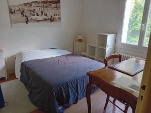 Un dormitorio con una cama, un escritorio y una mesa. en maison en banlieue de Caen, en Sept-vents