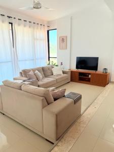 a living room with a couch and a television at Lar e Mar PG in Praia Grande