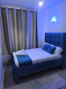 een slaapkamer met een groot blauw bed met gordijnen bij Poshairbnb in Nairobi