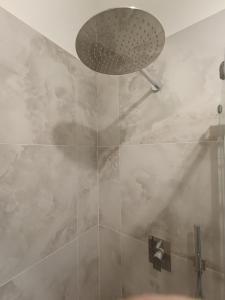 ducha con puerta de cristal y cabezal de ducha en Sidera, en Dervio