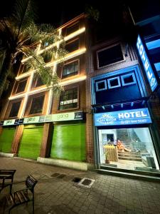 Un edificio de hotel con una fachada verde neón por la noche. en Hotel Plaza Mayor 44, en Medellín