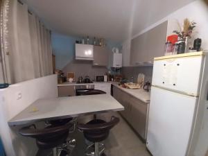 a kitchen with a white counter and stools in it at 100m lac et piste cyclable avec parking gratuit in Sévrier