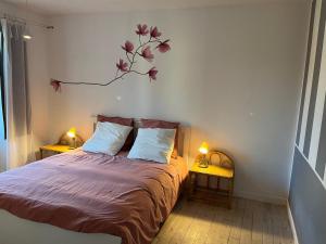 a bedroom with a bed with a branch on the wall at Gîte La maison bleue proche Epernay in Chaltrait