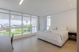 ein weißes Schlafzimmer mit einem Bett und großen Fenstern in der Unterkunft Casa de Luxo em Condomínio na Barra de São Miguel in Barra de São Miguel + 86 Fotos