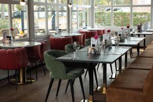 a row of tables in a restaurant with red chairs at Hotel 't Vertrek in Boxmeer