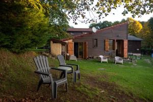 un groupe de chaises assises dans l'herbe devant une maison dans l'établissement Auberge Les Myrtilles, à Le Bosc