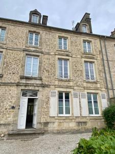 an old stone building with a white door and windows at Maison Cornat, Numéro 6, Le Duplex in Valognes
