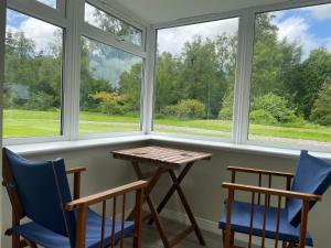 a table and two chairs in a room with windows at Woodside Cottage Self Catering in Kinbuck