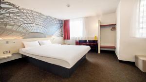a hotel room with a large white bed and a table at B&B HOTEL Katowice Centrum in Katowice