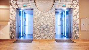 two blue elevators in a room with a wall at B&B HOTEL Katowice Centrum in Katowice