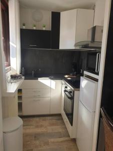 グレウー・レ・バンにあるStudio lumineux proche des thermes et du centre-village residence Parc Paradisの白いキャビネットと黒い壁のキッチン +2枚の写真