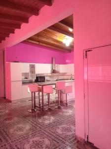 a pink kitchen with pink chairs and a table at Casa de campo Luisa in Tinogasta