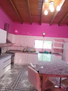 a kitchen with pink walls and a table in it at Casa de campo Luisa in Tinogasta