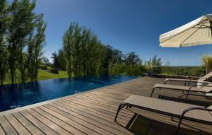a wooden deck with chairs and an umbrella next to a swimming pool at Edificio Q by depptö in Punta del Este