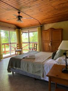 a bedroom with a bed with a ceiling fan and windows at Posada Quellen in Villa General Belgrano