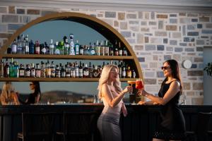 Dos mujeres de pie en un bar con bebidas en Argini Syros, en Ermoupoli