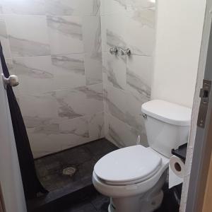 a bathroom with a white toilet and a shower at Tan cerca del mar! in Veracruz