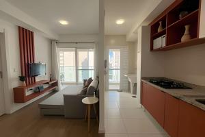 a kitchen and living room with a couch and a television at Pet Friendly - apto completo Gleba Palhano in Londrina