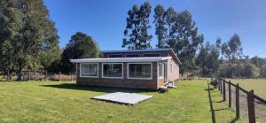 a small house in a field with a fence at Cabaña Alto Puelo in Puelo