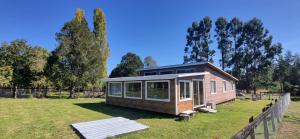 a small house in a field with a fence at Cabaña Alto Puelo in Puelo