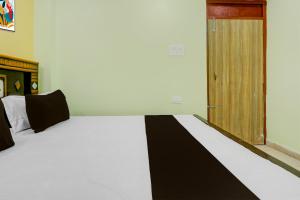 a bedroom with a white bed with a wooden door at Hotel O Ansh Raj Hotel in Patna City