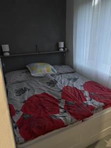 an unmade bed with red roses on it at Apartmánový byt VYHNE in Vyhne