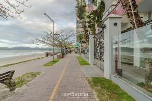 a sidewalk next to the beach with a bench at Aptos em Prédio à Beira-mar em Meia Praia, Itapema - EVBs in Itapema
