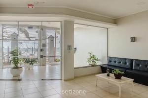 a lobby with a couch and plants in a building at Aptos em Prédio à Beira-mar em Meia Praia, Itapema - EVBs in Itapema