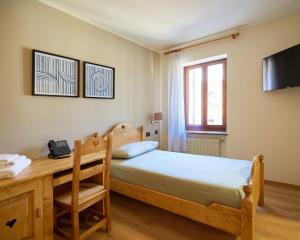 a bedroom with a bed and a desk with a telephone at Villa Alpina Hotel in Forni di Sopra