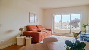 a living room with an orange chair and a window at Sea & City Escape in Matosinhos