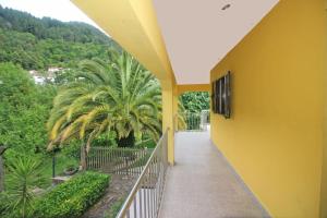 ein gelbes Gebäude mit einem Balkon mit einer Palme in der Unterkunft Casas da Paz by Gerês Casas in Geres