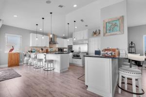 a kitchen with white cabinets and bar stools at Bella Vista by Gulf Coast Getaways in Pensacola Beach