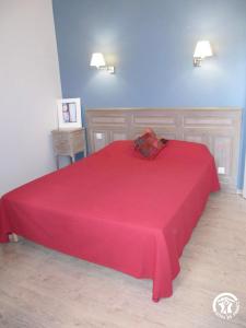 a red bed with a red blanket on top of it at Le Mas de la Tourelle in Roussennac