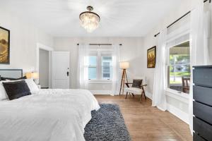 a white bedroom with a bed and a window at MidTown Cozy Cottage in Indianapolis
