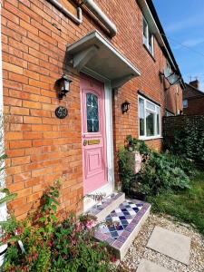 a pink door on the side of a brick house at House of Agnes in Yeovil