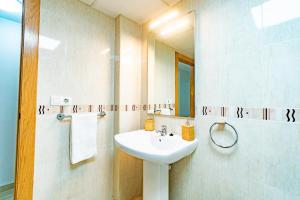 Un baño blanco con lavabo y espejo. en Avenida Principal con Aire Acondicionado, Wifi y Parking - by Aloha Palma, en Águilas 27 fotos más