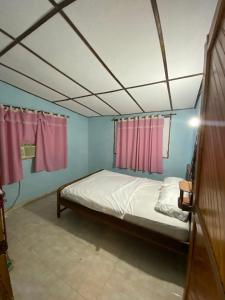 a bed in a room with pink curtains at Cabaña el encanto in Santa Marta +1 photo