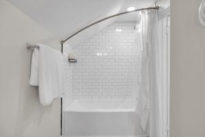 a white bathroom with a shower and a shower curtain at MidTown Cozy Cottage in Indianapolis +69 photos