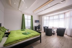 Schlafzimmer mit einem grünen Bett, einem Tisch und Stühlen in der Unterkunft Max Aviation Villa & Apartments in Bern