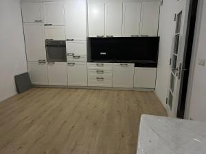 a kitchen with white cabinets and a flat screen tv at Banesa Mitrovice in Mitrovicë +1 photo