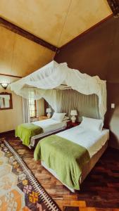 2 camas en un dormitorio con dosel en The River Villa, en Magaliesburg