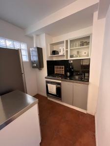 une cuisine avec des armoires blanches et un four à plaques de cuisson dans l'établissement Oroño Estudio Departamento de 1 habitacion, à Rosario